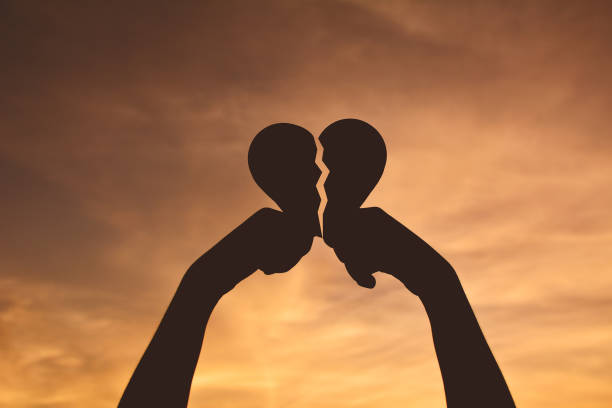 istock Cropped Image Of Hands Holding Broken Heart Shape Against Dramatic Sky 697630817