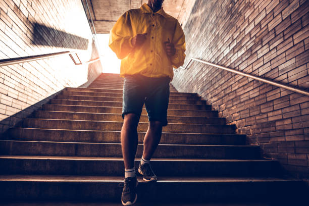 istock Sporty man running up steps in urban setting 697631044