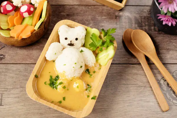 Photo of Creative idea for kids lunch or dinner. Children animal food. Bath with rice bear and cream soup. Mushrooms of radishes, shaped flowers from cucumbers and carrots. Fun and healt
