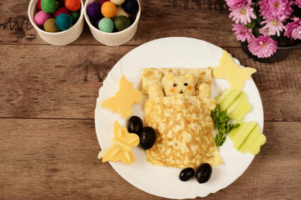 istock Creative idea for kids snack, breakfast or lunch. Sleeping bear from bulgur, rice and quinoa under the blanket of egg omelet. Flowers and butterflies with cucumber, sandwiches of cheese and bread. Fun and healthy kids meal. Art of food 697640962