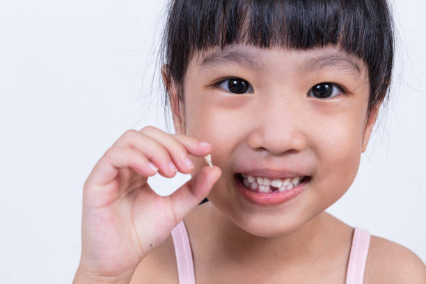 istock Asian Chinese little girl holding her missing tooth 697646798