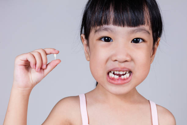istock Asian Chinese little girl holding her missing tooth 697646814