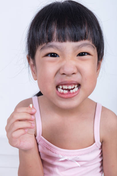 istock Asian Chinese little girl holding her missing tooth 697646816