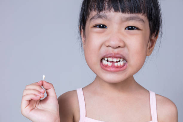 istock Asian Chinese little girl holding her missing tooth 697646818