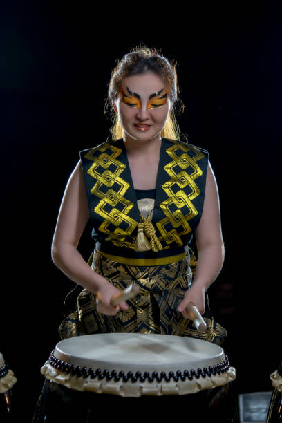istock beautiful asian drummer girl with drumsticks, studio shot on a dark background. 697647534