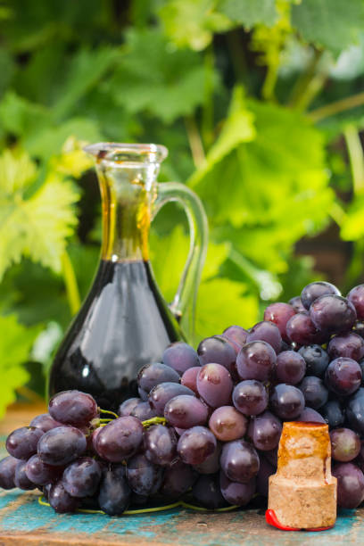 negro viejo vinagre balsámico en una jarra de cristal con uvas rojas sobre fondo verde viña - balsamic vinegar bottle vinegar red wine fotografías e imágenes de stock