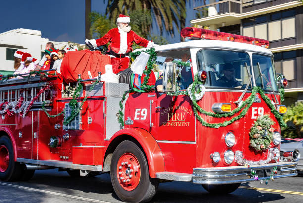Fire fighters dressed as Santa ride decorated fire engine during traditional Christmas Parade in Santa Monica, California.