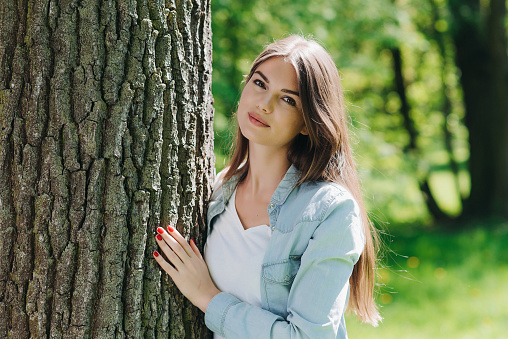 Young woman hugging a big tree, love nature concept