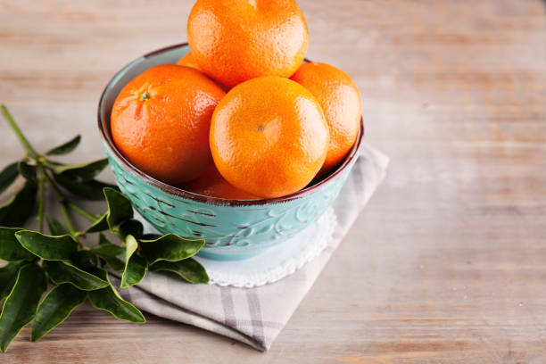 istock Mandarins Fruit with Green Leaves on Old Rustic Wooden Board Background 697658248