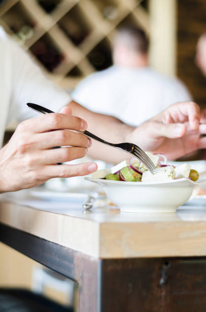 istock Greek salad, woman's hand and a fork on a table in a restaurant 697664826