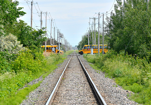 2 school buses crossing railroad tracks