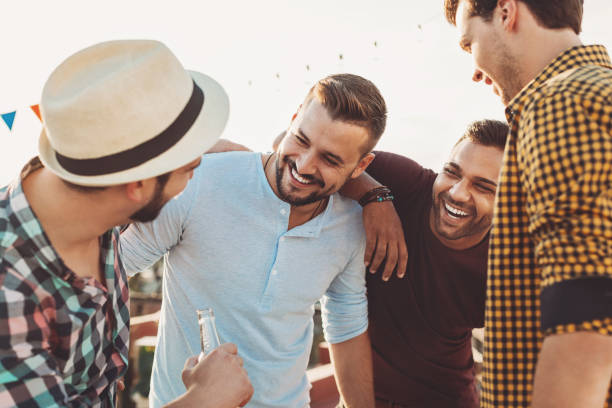 Four guys having fun Group of young men drinking beer and chatting on a party stag night stock pictures, royalty-free photos & images