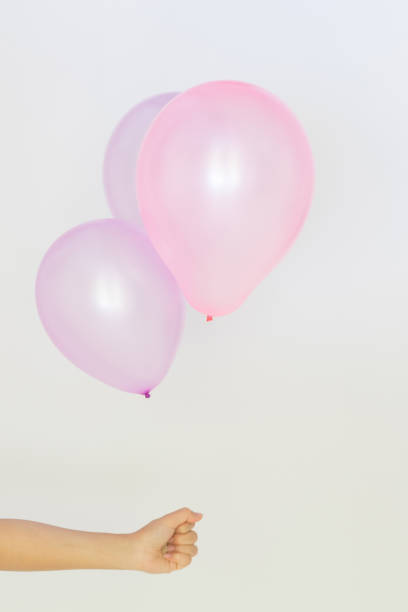 istock Womans hand holds balloons in a white background 697682676