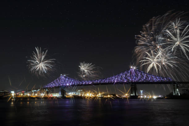 istock Colorful fireworks explode over bridge, reflection in water. Montreal’s 375th anniversary. luminous colorful interactive Jacques Cartier Bridge. Bridge panoramic colorful silhouette by night. 697695130