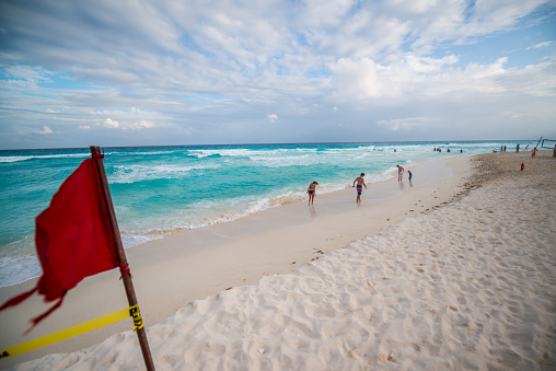 Cancun, Mexico - January 02, 2017: Red flag on Cancun beach, people enjoying the beach on background
