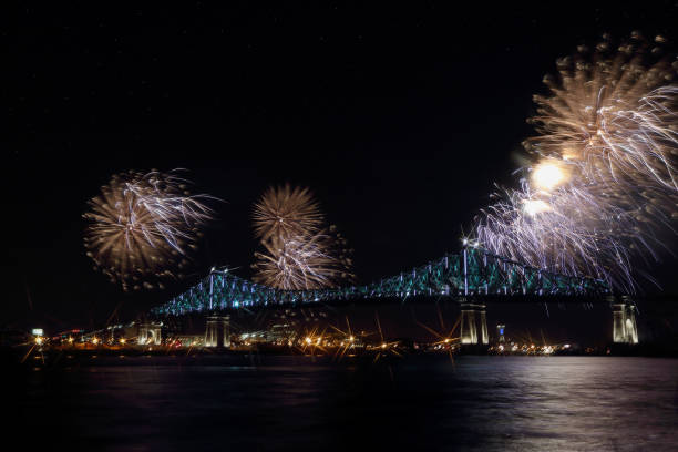 Colorful fireworks explode over bridge, reflection in water. Montreal’s 375th anniversary. luminous colorful interactive Jacques Cartier Bridge. Bridge panoramic colorful silhouette by night. Colorful fireworks explode over bridge, reflection in water. Montreal’s 375th anniversary. luminous colorful interactive Jacques Cartier Bridge. Bridge panoramic colorful silhouette by night. 150th anniversary stock pictures, royalty-free photos & images