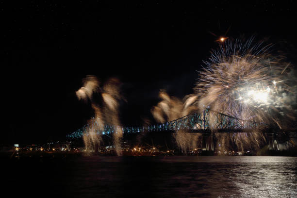 istock Colorful fireworks explode over bridge, reflection in water. Montreal’s 375th anniversary. luminous colorful interactive Jacques Cartier Bridge. Bridge panoramic colorful silhouette by night. 697702326