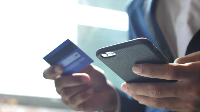Businessman inserting credit card number on mobile phone, Slow motion