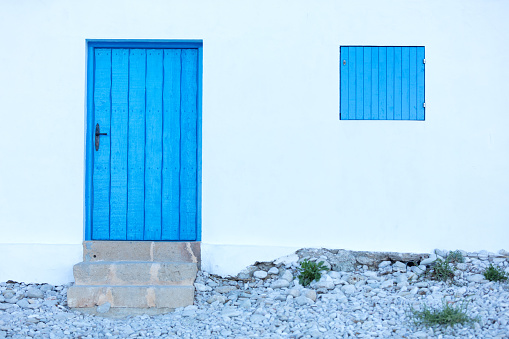 intense blue wooden door in a white wall, mediterranean colors