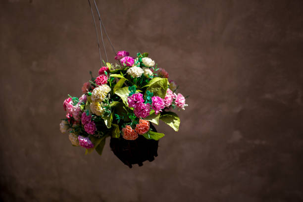 A flower in the flower jar hanging on the unknown support is flying while the wind is blowing.