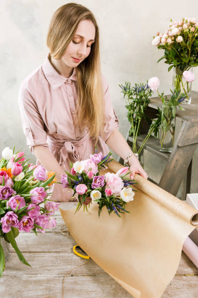 istock Woman packing pink spring bouquet top view 697716442