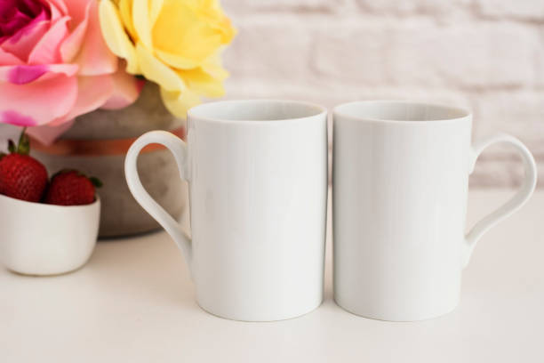 istock Two Mugs. White Mugs Mockup. Blank White Coffee Mug Mock Up. Styled Photography. Coffee Cup Product Display. Two Coffee Mugs On White Desk. Vase With Pink Roses 697722554