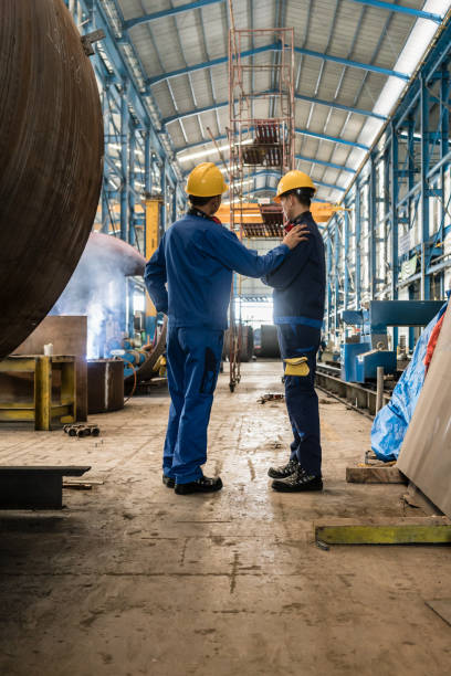 istock Two workers wearing yellow hard hat and blue uniform 697723062