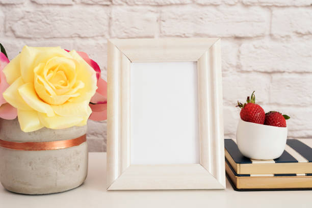 istock Frame Mockup. White Frame Mock up. Cream Picture Frame, Vase With Pink Roses, Strawberries on Stripe Notebooks. Product Frame Mockup. Wall Art Display Template, Brick Wall 697725774