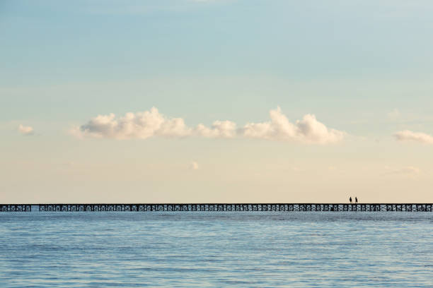 istock Two children walking on a boardwalk in the sea. 697726428