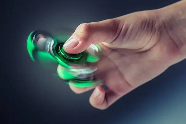 Photo of Fidget Spinner. Green fidget pinner in a girl hand