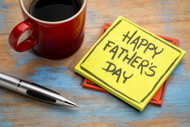 happy father's day - handwriting in black ink on a sticky note with a cup of coffee