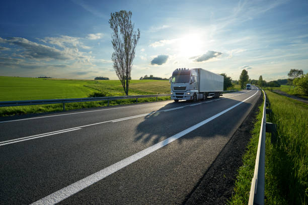 istock White trucks driving on asphalt road in landscape at sunset 697756636