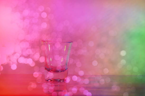 single shot glass for party with glowing pink bokeh background