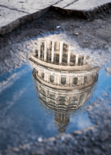 istock Reflection, in a broken sidewalk puddle, of the Capitol building in Cuba 697764188