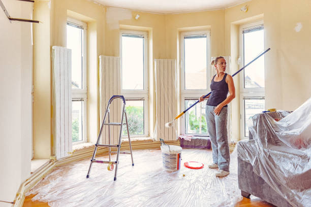 istock Young woman taking break from painting walls with telescopic roller 697766496