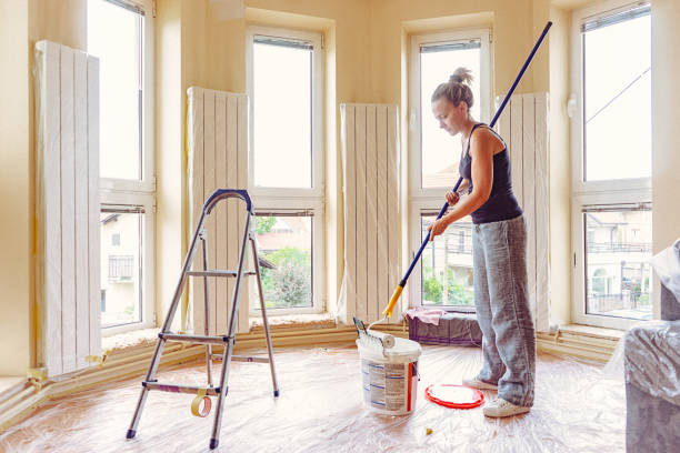 istock Young woman dipping paint roller in  paint. 697766510