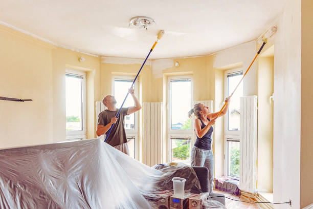 istock Couple painting wall and ceiling with telescopic roller 697766590