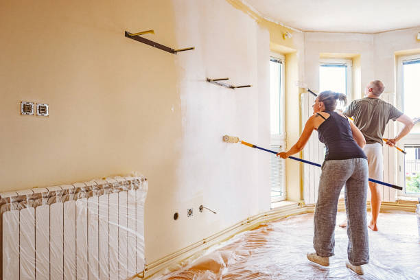 istock Couple painting walls with telescopic roller. 697766678