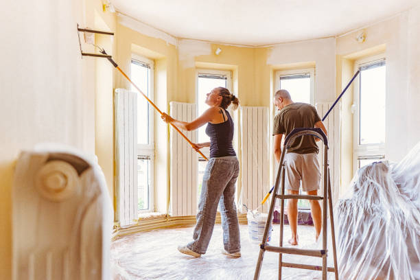 istock Couple painting wall and ceiling with telescopic roller 697766680