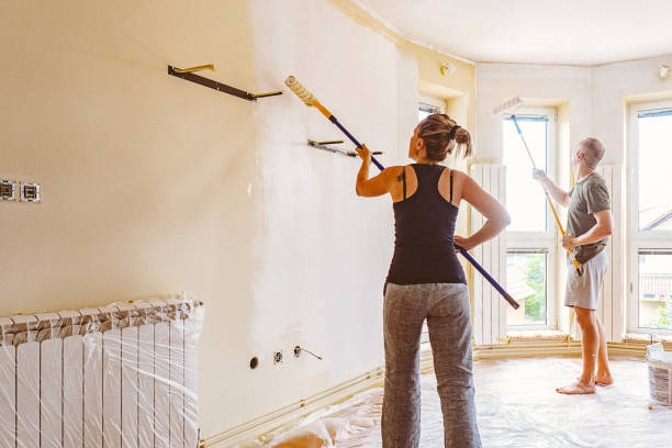 istock Couple painting wall and ceiling with telescopic roller. 697766732