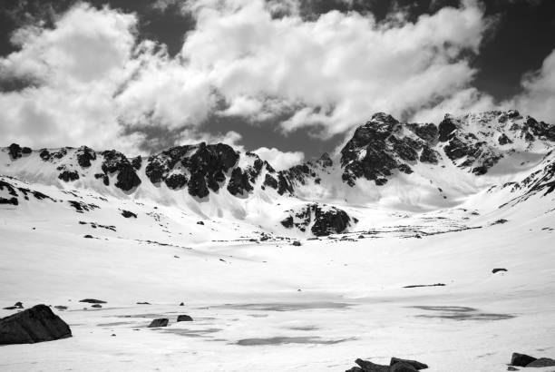 istock Black and white view on frozen mountain lake covered with snow 697769722