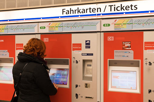 Woman buys a ticket for public transport in a vending machine, Hamburg, Germany. In Hamburg, there is a single ticket for different types of transport: the metro, the train, the bus or the river ferry.