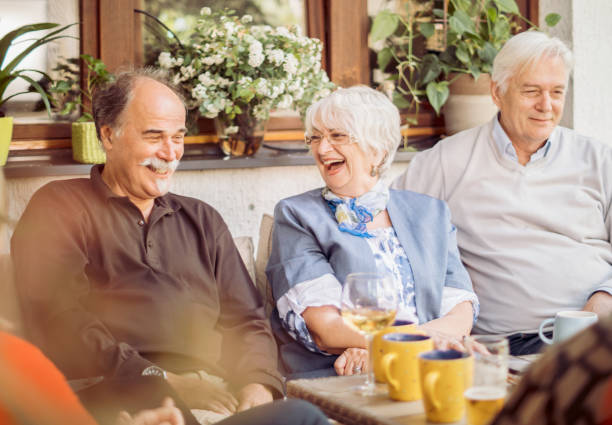Social Seniors Group Of Mature Friends Enjoying Outdoor Meal In Backyard Group Of Mature Friends Enjoying Outdoor Meal In Backyard prosperity photos stock pictures, royalty-free photos & images