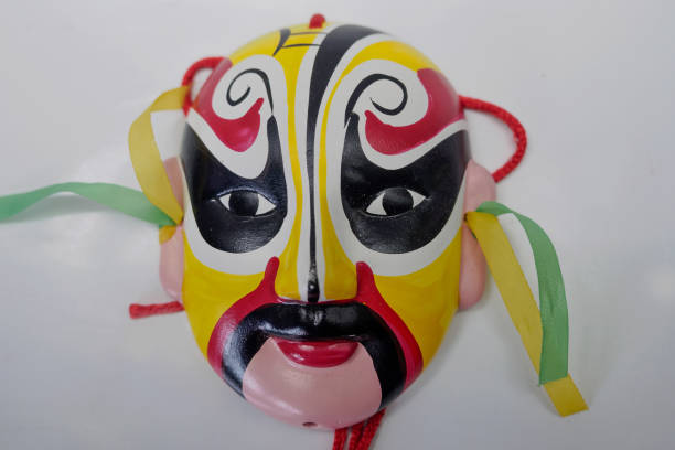A beige realistic papier-mache mask with sun symbol on forehead lies on a wooden surface among various wooden ornaments