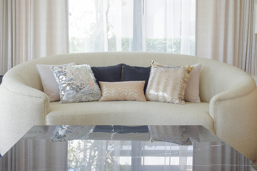 Round shape sofa with luxury style pillows and marble top table in foreground