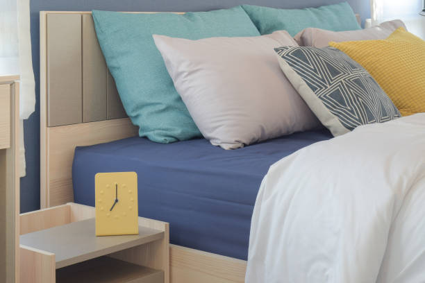 istock Yellow and green pillow setting on bed with modern style yellow clock on bed side table 697798636