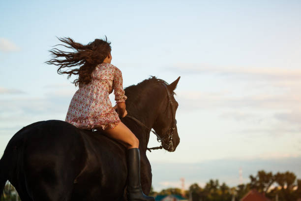 Blond hair woman riding horse on sunny day