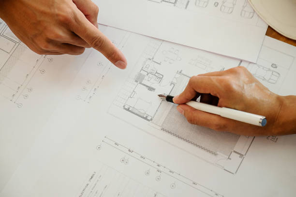 istock Architects engineer discussing at the table with blueprint - Closeup on hands and project print. 697806096