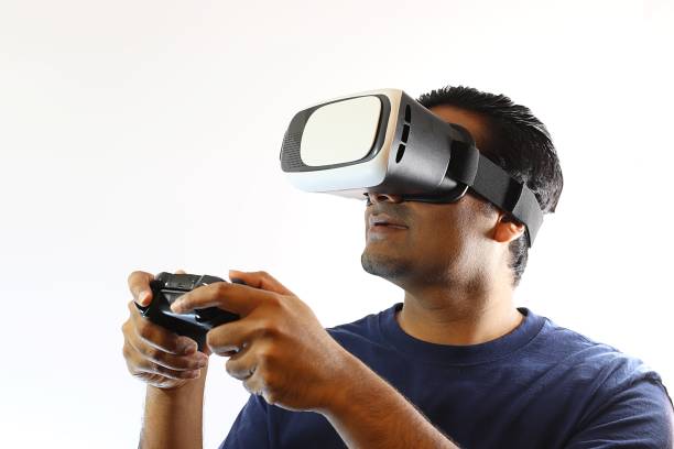 istock Young handsome man wearing virtual reality goggles standing against white background 697808296