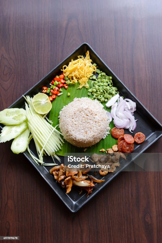 Thai food - Rice mixed with shrimp paste (Kao Cluk Ka Pi) with side dish as a mango, lemon, chili, cucumber, scrambled egg, cow-pea, shallots, Chinese sausage, dried shrimp and pork Asia Stock Photo